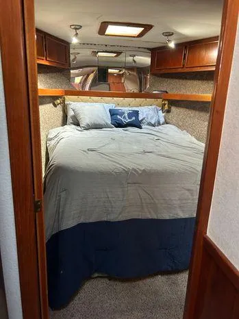 Slide: The Image of 1989 Post 43 Sport Fisherman cabin with cozy bed, wooden cabinets, and nautical decor. - 30