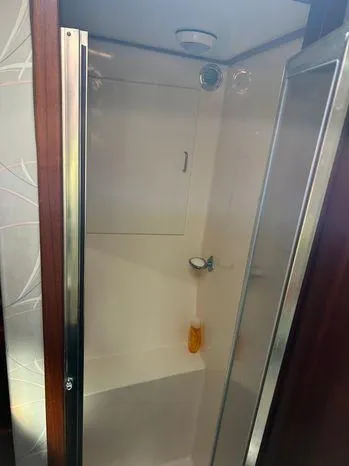 Slide: The Image of Shower area inside 1989 Post 43 Sport Fisherman boat, featuring glass door and wooden trim. - 35