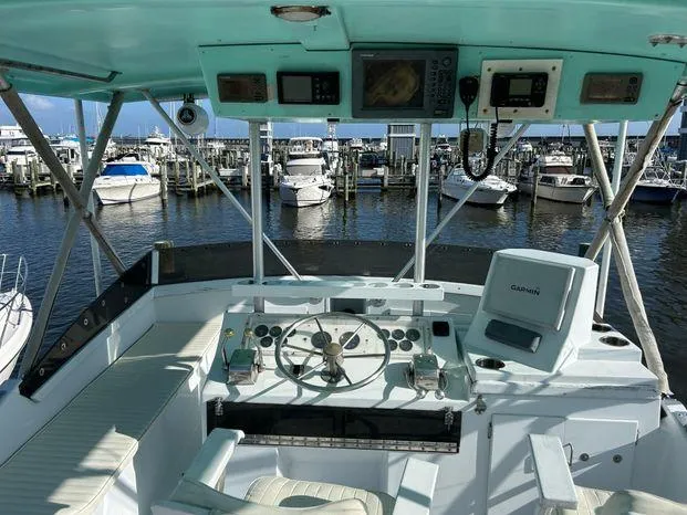 Slide: The Image of 1989 Post 43 Sport Fisherman boat cockpit with steering wheel, electronics, and marina view. - 9