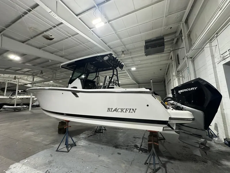 Slide: The Image of 2025 Blackfin 272CC boat in indoor storage, featuring Mercury outboard engine. - 2