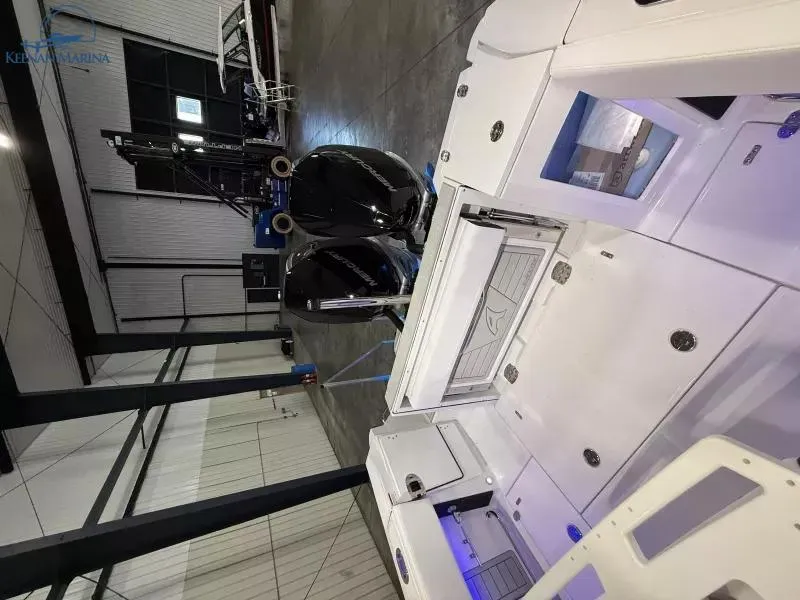 Slide: The Image of 2025 Blackfin 272CC boat in a modern indoor marina setting. - 3