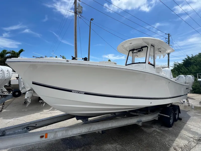 Slide: The Image of 2023 Regulator 26XO boat on trailer under clear blue sky. - 0