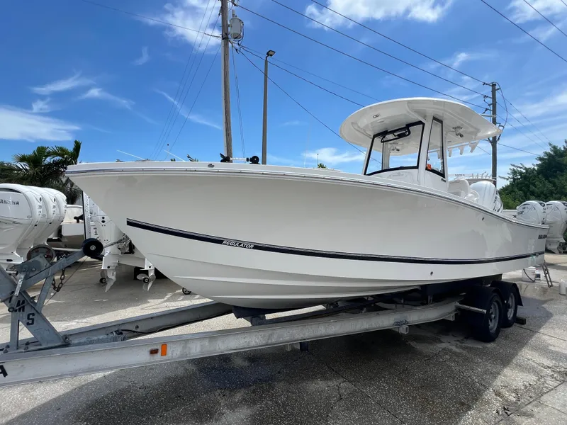 Slide: The Image of 2023 Regulator 26XO boat on trailer under clear blue sky. - 1