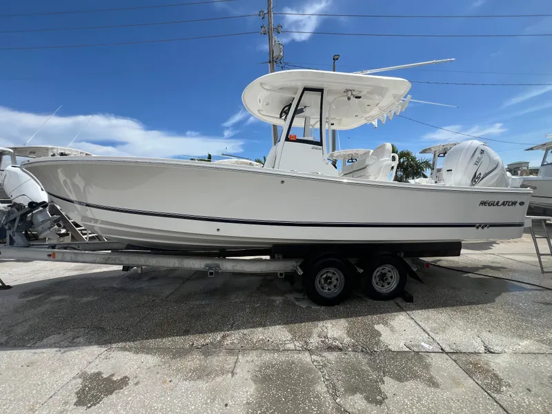 Slide: The Image of 2023 Regulator 26XO boat on trailer under clear blue sky. - 2