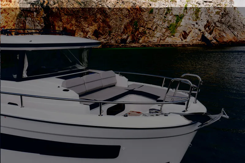Slide: The Image of 2026 Jeanneau NC895 Sport S2 yacht near rocky coastline. - 2