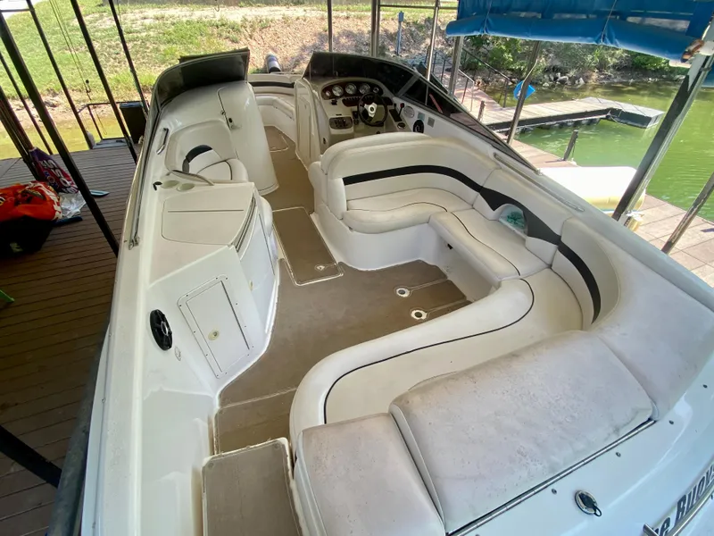 Slide: The Image of 2000 Chaparral 280 SSi boat interior with spacious seating and helm, docked by the water. - 23