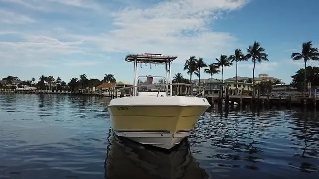 Slide: The Image of 2005 Cobia 214 CC boat on calm water with palm trees in the background. - 10