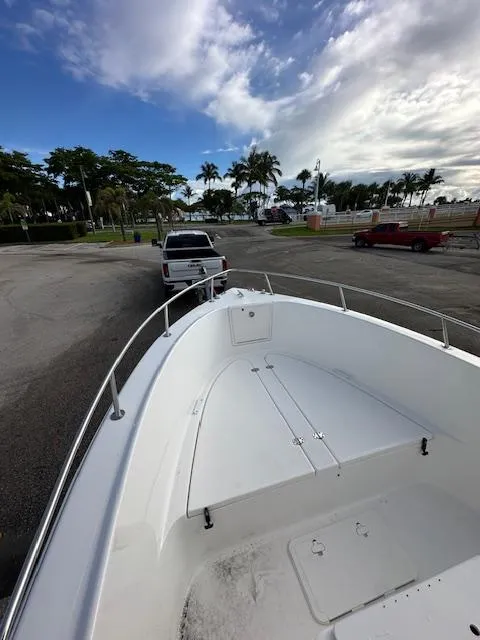 Slide: The Image of 2005 Cobia 214 CC boat on trailer, parked near palm trees under a partly cloudy sky. - 13