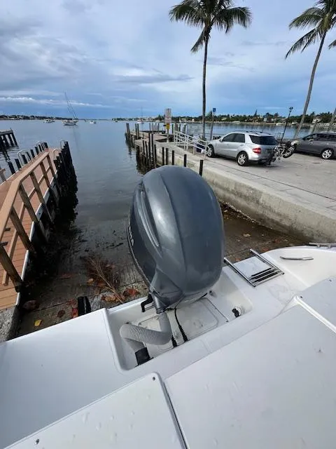 Slide: The Image of 2005 Cobia 214 CC boat with outboard motor docked by a scenic waterfront. - 18