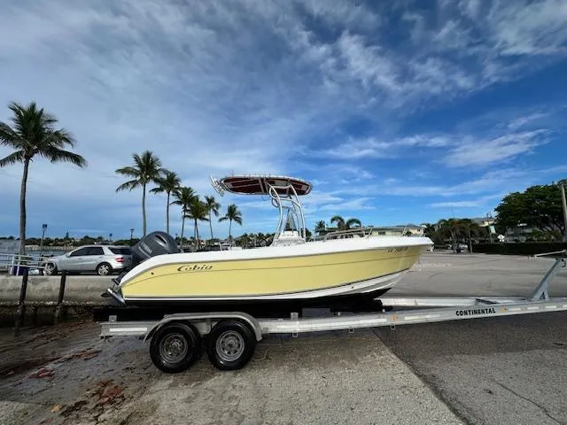 Slide: The Image of 2005 Cobia 214 CC boat on trailer, parked near palm trees under a blue sky. - 19