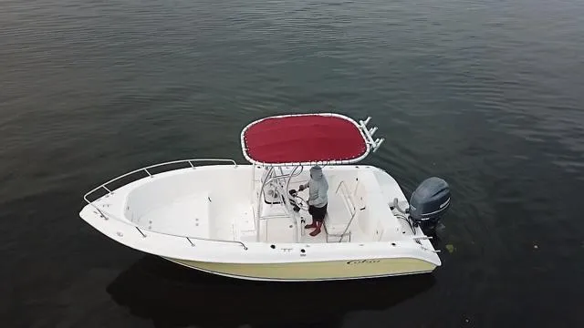 Slide: The Image of 2005 Cobia 214 CC boat with red canopy on calm water. - 2