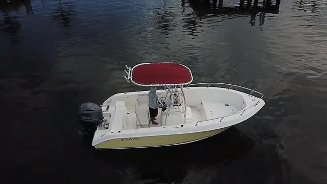 Slide: The Image of 2005 Cobia 214 CC boat with red canopy on calm water. - 4