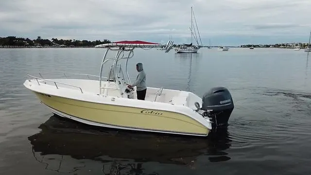 Slide: The Image of 2005 Cobia 214 CC boat on calm water with a person at the helm. - 6
