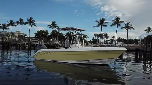 Slide: The Image of 2005 Cobia 214 CC boat on calm water with palm trees in the background. - 9