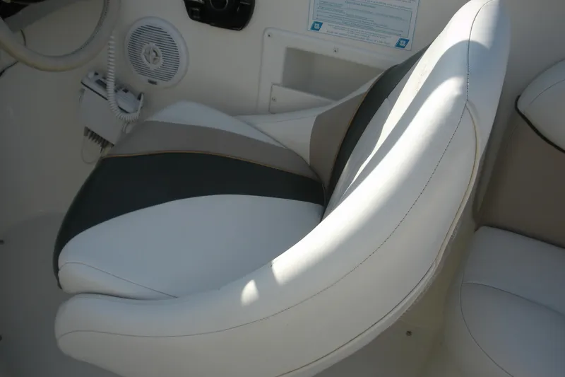Slide: The Image of 1999 Rinker 232 Captiva Cuddy boat interior with cushioned seating and control panel. - 14