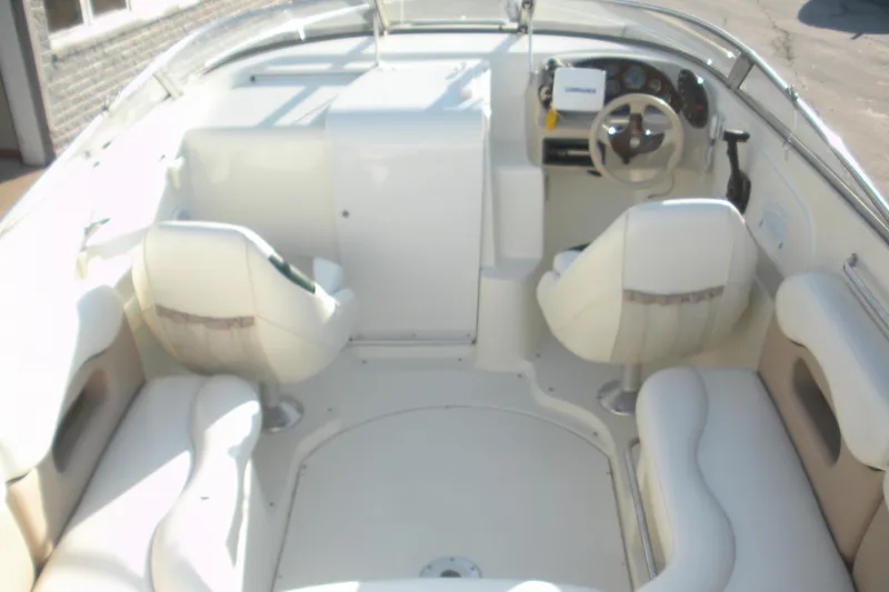 Slide: The Image of 1999 Rinker 232 Captiva Cuddy boat interior with white seating and steering console. - 16