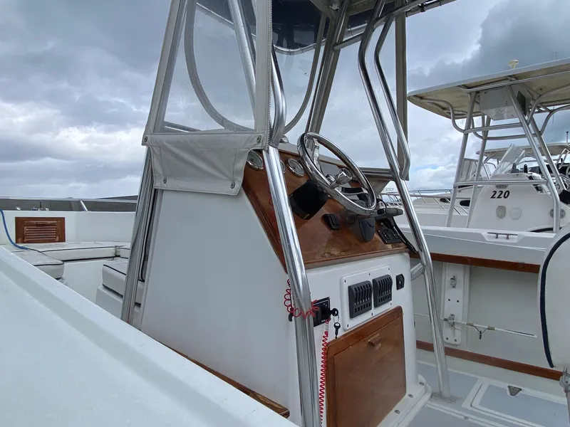 Slide: The Image of 1991 Mako 241 boat console with steering wheel, under cloudy sky. - 13