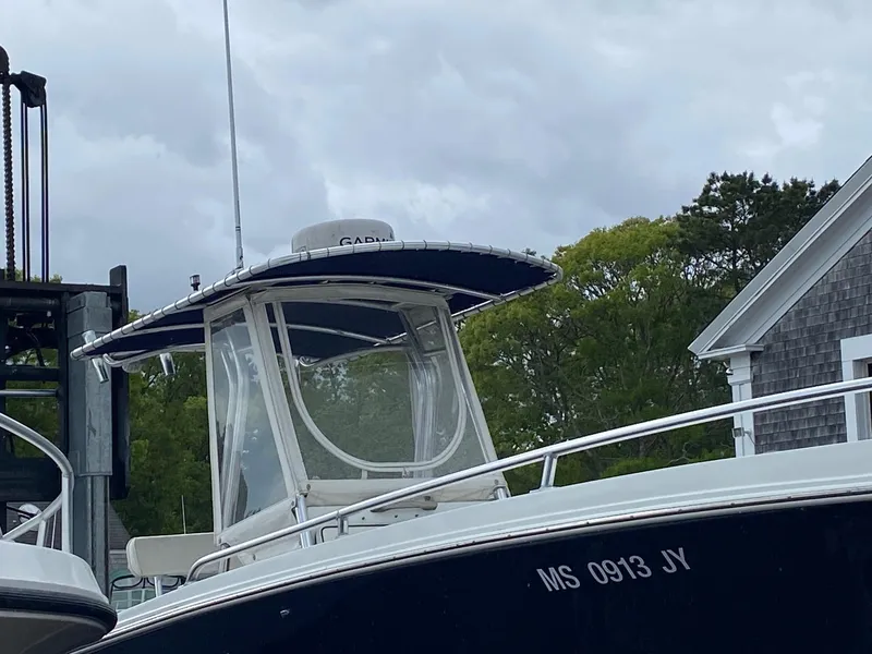 Slide: The Image of 1991 Mako 241 boat with canopy, docked near a building, overcast sky. - 19