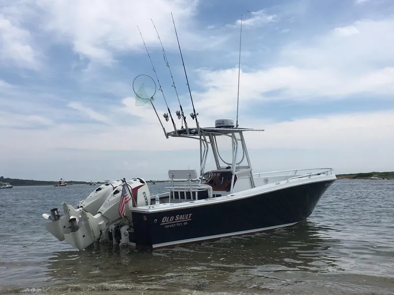 Slide: The Image of 1991 Mako 241 boat with fishing gear, docked in shallow water under a cloudy sky. - 2