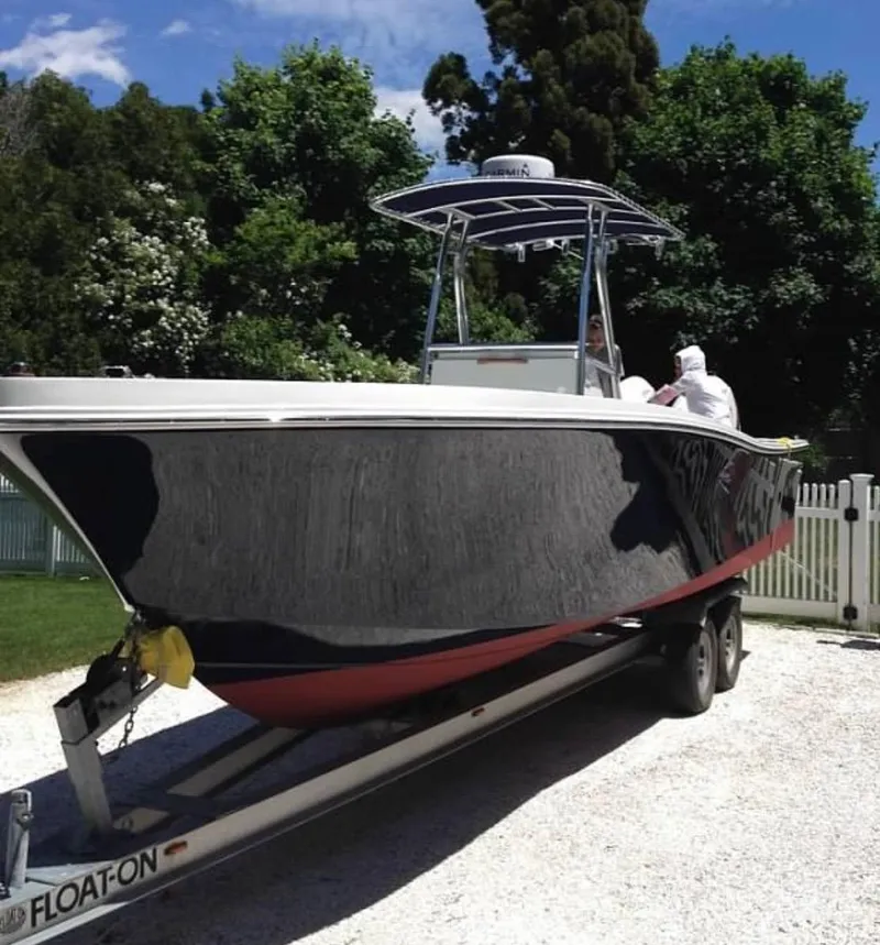 Slide: The Image of 1991 Mako 241 boat on trailer, surrounded by trees and blue sky. - 29