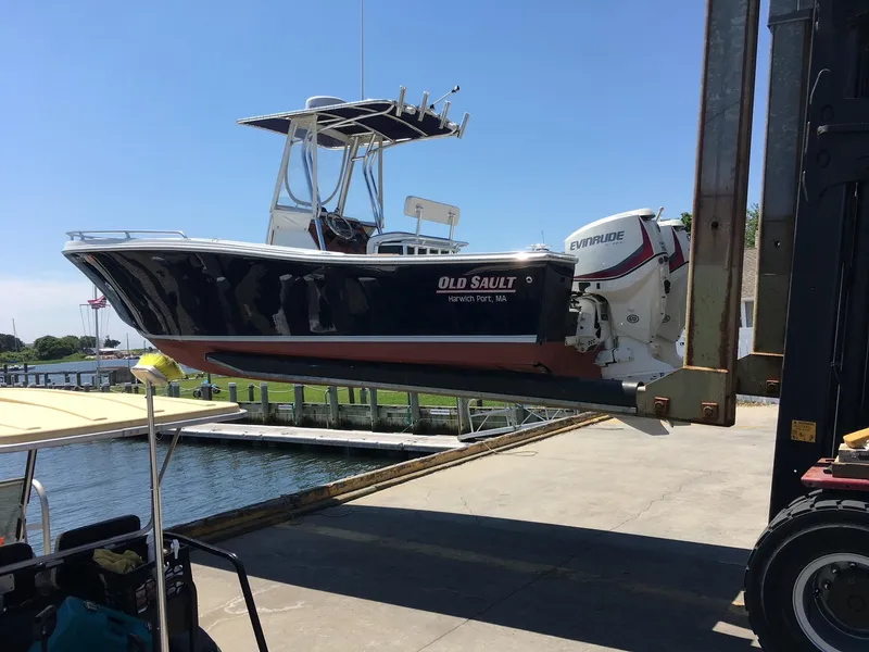 Slide: The Image of 1991 Mako 241 boat lifted by forklift at marina, featuring Evinrude engine. - 30
