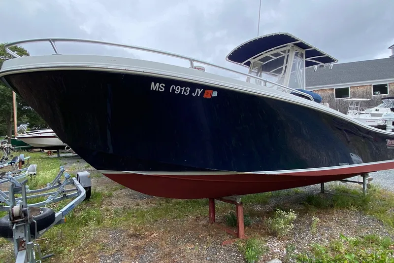 Slide: The Image of 1991 Mako 241 boat with dark blue hull on a trailer, parked outdoors. - 32