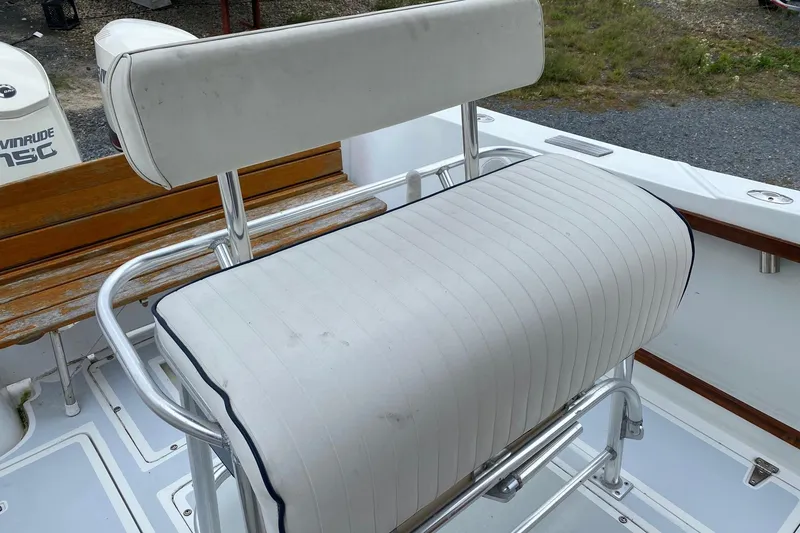 Slide: The Image of White cushioned seat on a 1991 Mako 241 boat with metal frame and wooden accents. - 36