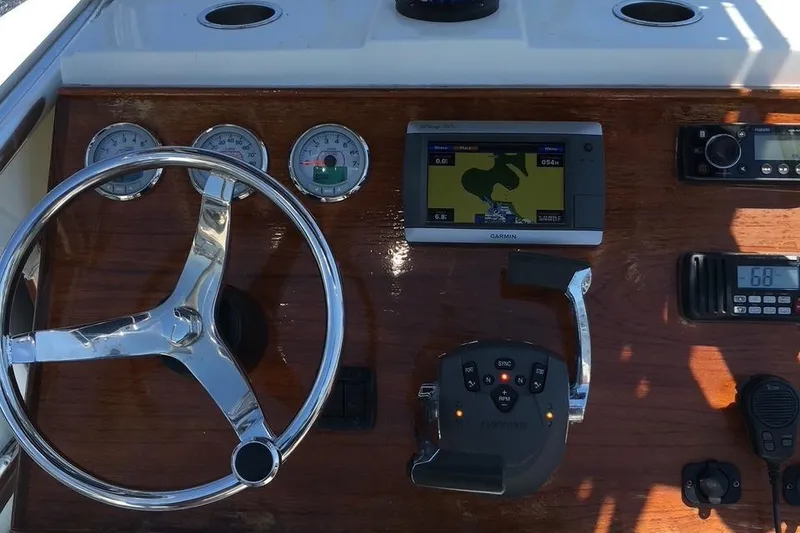 Slide: The Image of 1991 Mako 241 boat dashboard with steering wheel, gauges, GPS, and radio controls. - 6