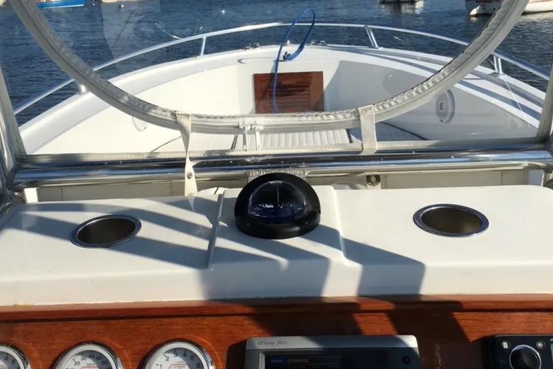 Slide: The Image of 1991 Mako 241 boat dashboard with compass, cup holders, and gauges on a sunny day. - 7