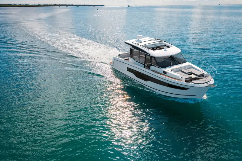 Slide: The Image of 2026 Jeanneau NC 1095 S2 cruising on clear blue water under sunny skies. - 2