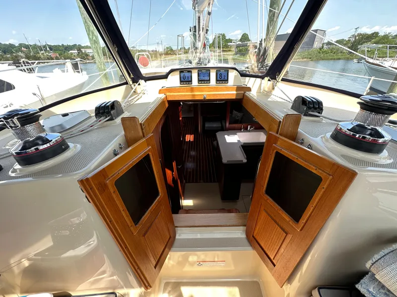 Slide: The Image of Cockpit view of 2021 Island Packet 439 sailboat, showcasing navigation instruments and wooden cabin doors. - 28