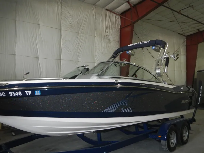 Slide: The Image of 2013 MasterCraft X30 boat on trailer in indoor storage facility. - 2