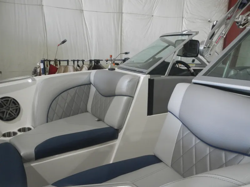 Slide: The Image of 2013 MasterCraft X30 boat interior with gray and blue seating, diamond stitching, and cup holders. - 6