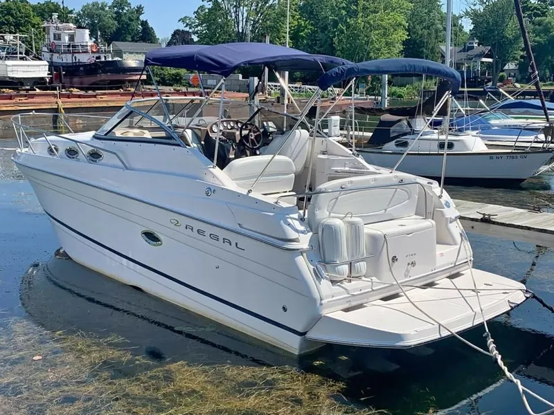 Slide: The Image of 2005 Regal Commodore 2765 boat docked in a marina, featuring white exterior and blue canopy. - 2