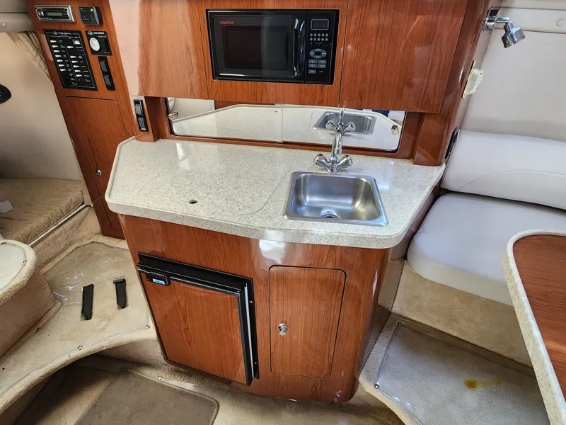 Slide: The Image of 2005 Regal Commodore 2765 boat interior with kitchenette, featuring sink, microwave, and mini-fridge. - 22