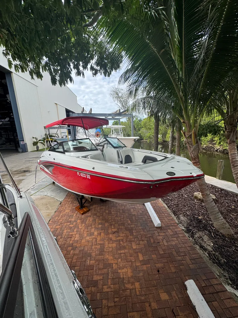 Slide: The Image of Red 2020 Monterey M65 boat with canopy, parked near tropical trees and waterway. - 20