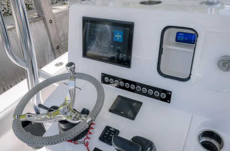 Slide: The Image of 2024 Contender 26 Bay boat dashboard with steering wheel and electronic controls. - 26