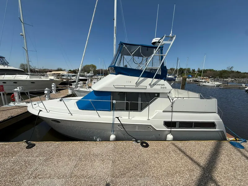 Slide: The Image of 1996 Carver 325 Aft Cabin yacht docked at marina under clear blue sky. - 0