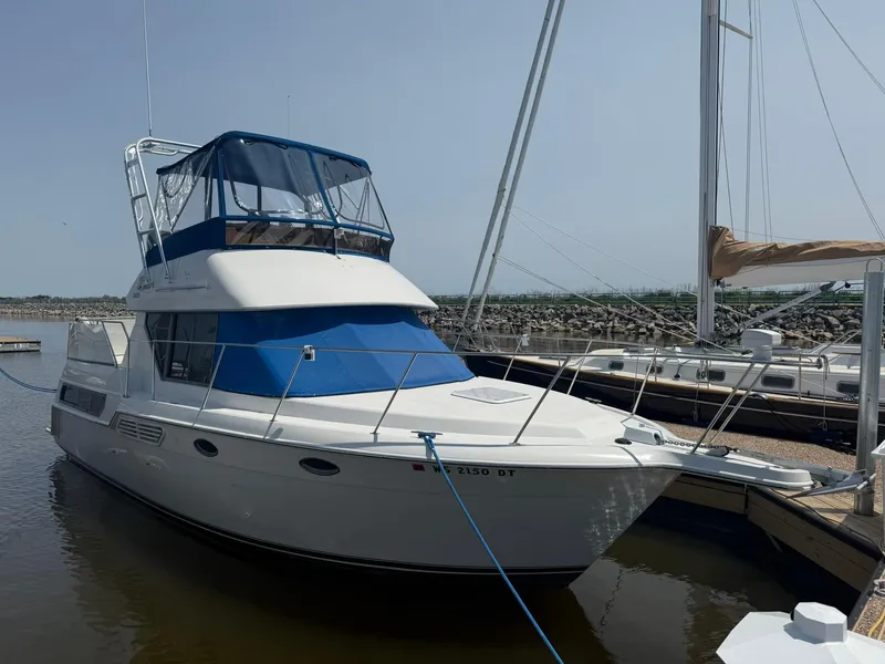 Slide: The Image of 1996 Carver 325 Aft Cabin yacht docked at marina, featuring blue canopy and sleek design. - 1