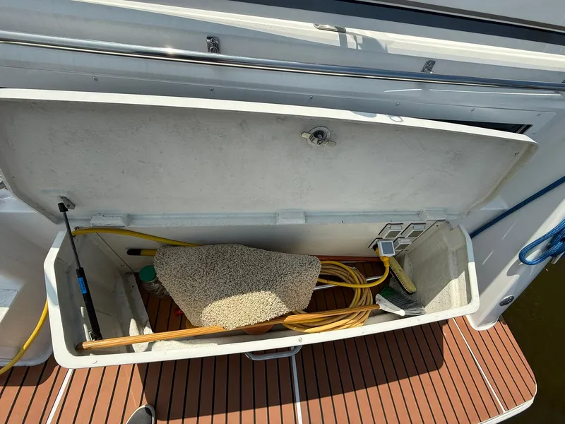 Slide: The Image of 1996 Carver 325 Aft Cabin storage compartment with cleaning supplies and hose. - 11