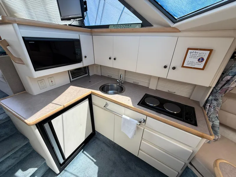 Slide: The Image of 1996 Carver 325 Aft Cabin kitchen with microwave, sink, stove, and cabinets. - 19