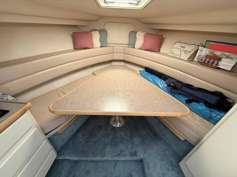 Slide: The Image of 1996 Carver 325 Aft Cabin interior with triangular table, cushioned seating, and decorative pillows. - 20