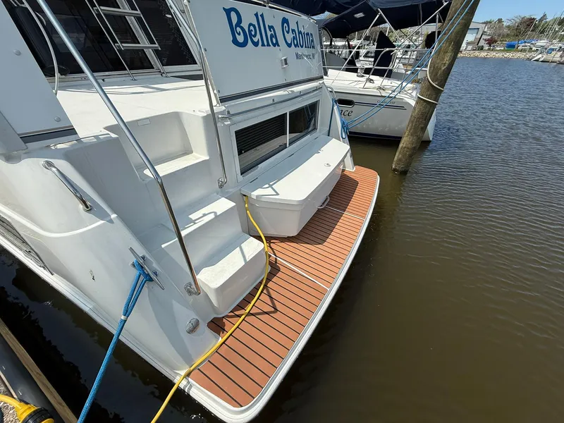 Slide: The Image of 1996 Carver 325 Aft Cabin boat docked, featuring a wooden swim platform and "Bella Cabina" name. - 9