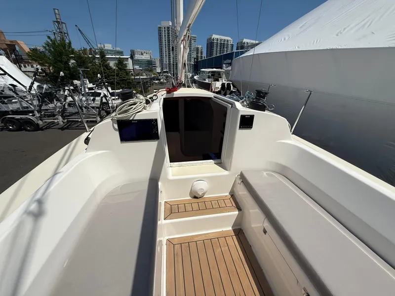 Slide: The Image of 2022 J Boats J/9 sailboat cockpit with wooden flooring, docked in a marina. - 15