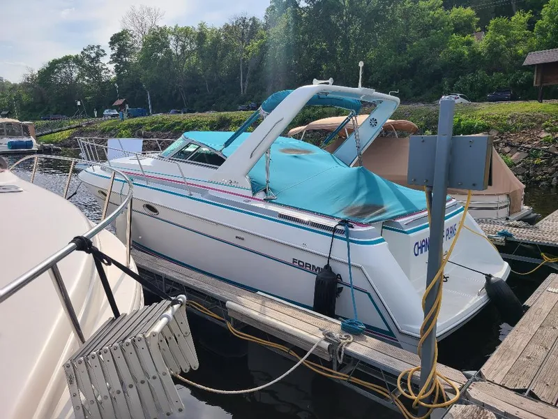 Slide: The Image of 1994 Formula 31 PC boat docked, featuring a blue cover and sleek design. - 1