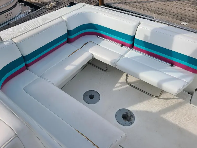 Slide: The Image of 1994 Formula 31 PC boat interior with white, teal, and pink seating on a dock. - 5