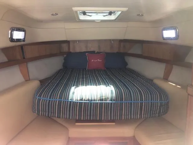 Slide: The Image of 2005 Mainship 30 Pilot Rum Runner cabin with striped bedding and portholes. - 3