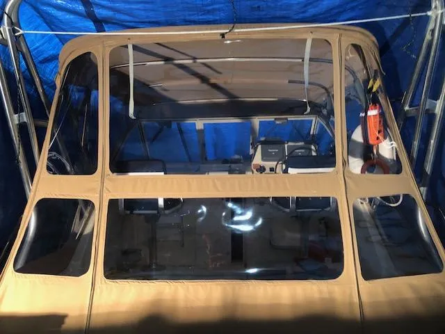 Slide: The Image of 2005 Mainship 30 Pilot Rum Runner with tan canopy and clear windows, under blue tarp. - 7