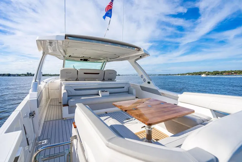 Slide: The Image of 2022 Tiara Yachts 43 LS, luxury deck view, wooden table, open water, blue sky. - 8