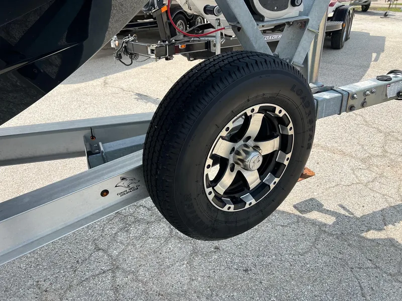 Slide: The Image of Trailer wheel of a 2018 Robalo 246 Cayman boat on pavement. - 2